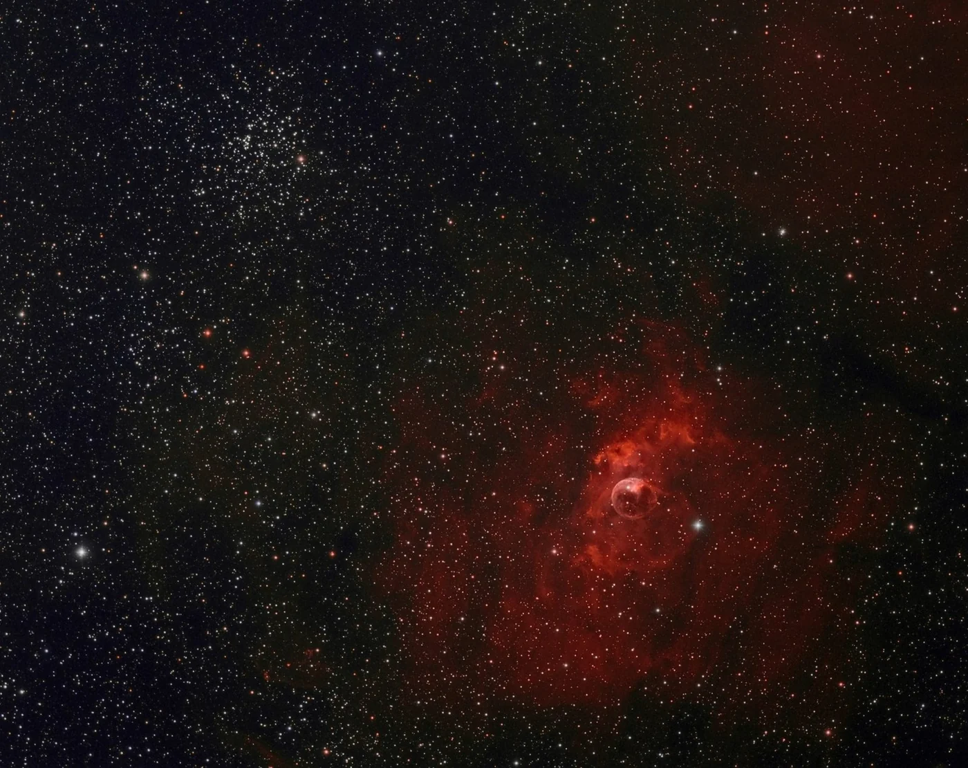 The Bubble Nebula, a sphere of red gas among thousands of stars, with the cluster M52 at the top left