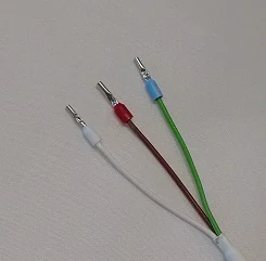 The three cable tips of the Sharp distance sensor side by side: one white, one brown, one green, each ending in a metal pin