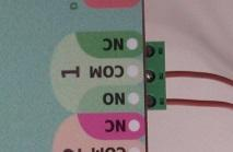 Relay 1 output terminals close-up: NC, COM and NO, with the roof motor's two wires attached