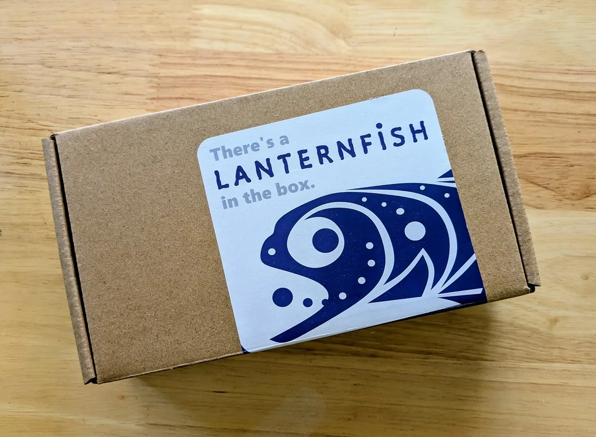 The Lanternfish box, in cardboard, with a sticker that reads: There's a Lanternfish in the box